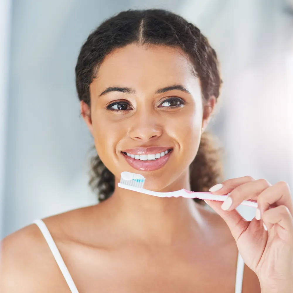 Woman brushing her teeth as part of a healthy dental routine